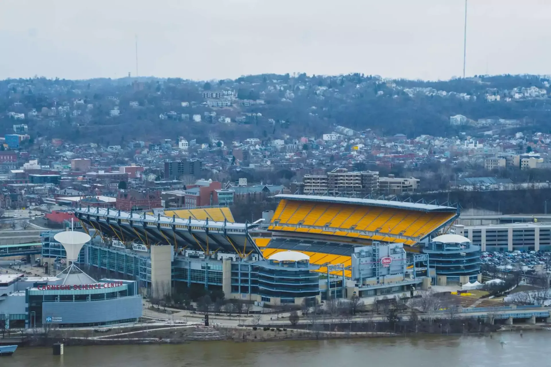 An aerial view of a city with a large yellow stadium in the middle of it.