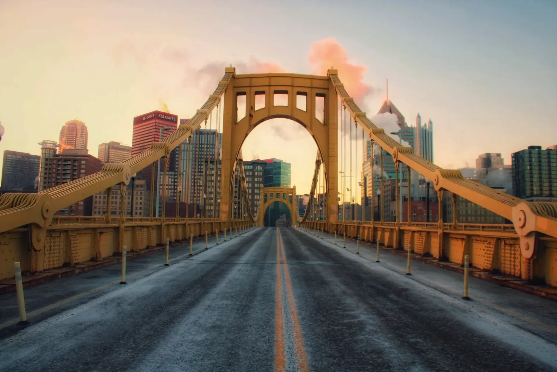 A bridge over a road with a city in the background.