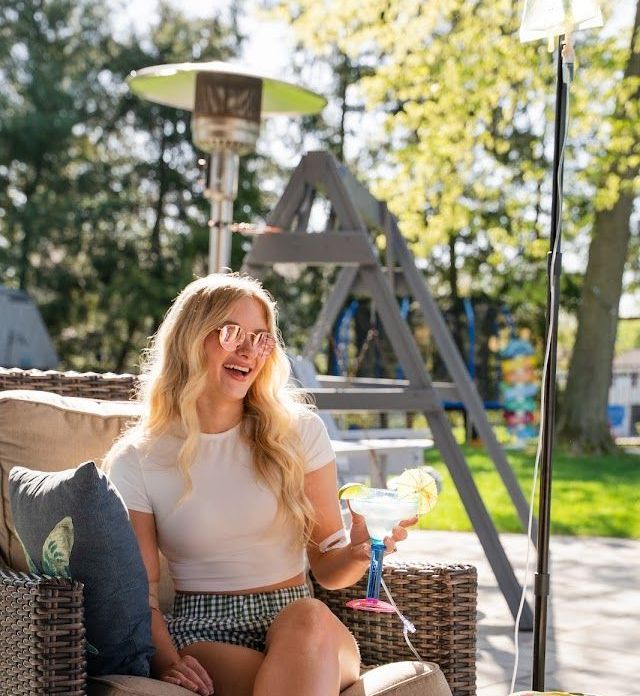A woman is sitting in a chair holding a drink.