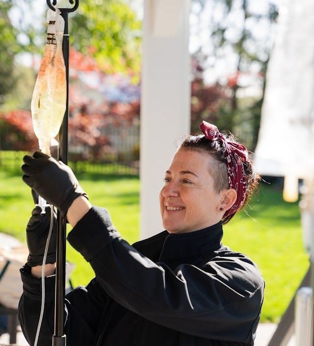 A woman wearing black gloves is holding an iv bag.