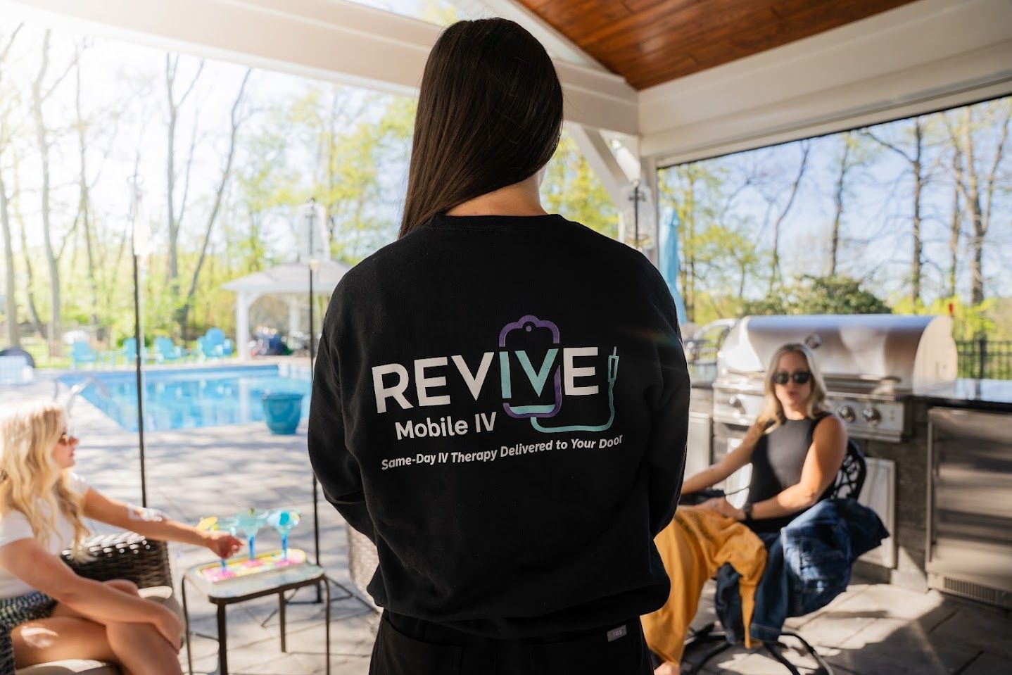 A woman wearing a black shirt with the word revive on it is standing in front of a group of people.