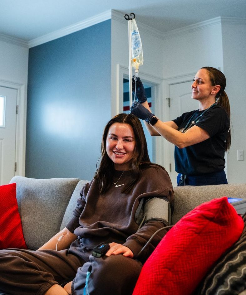 A woman is sitting on a couch with a man standing behind her.