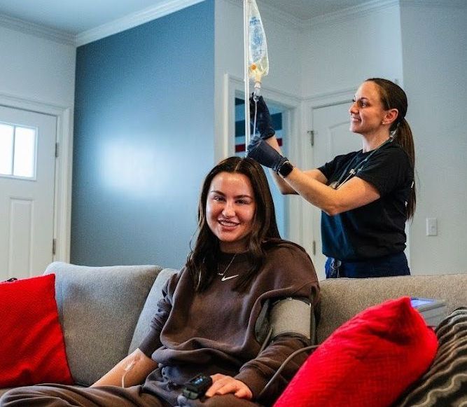 A woman is sitting on a couch with an IV.