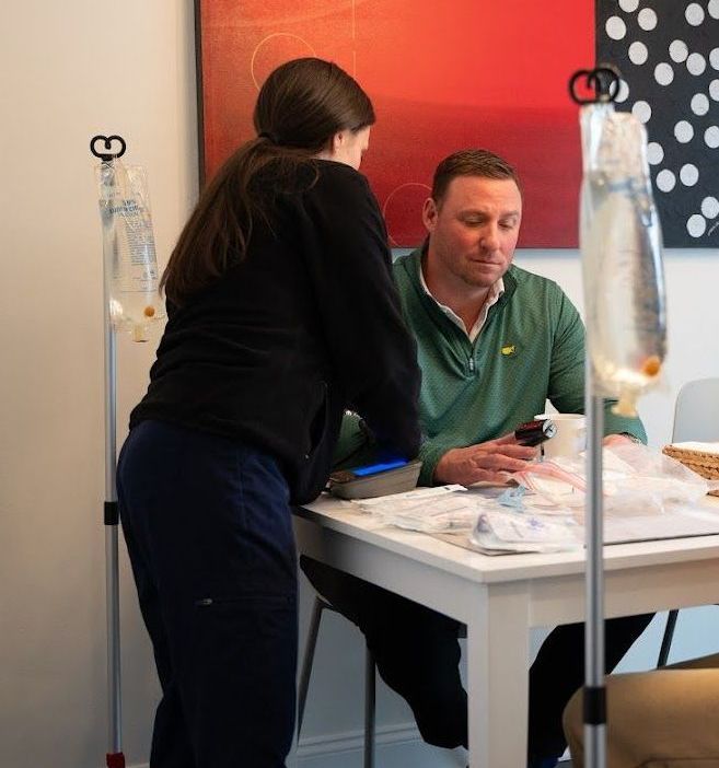 A woman is standing next to a man sitting at a table.