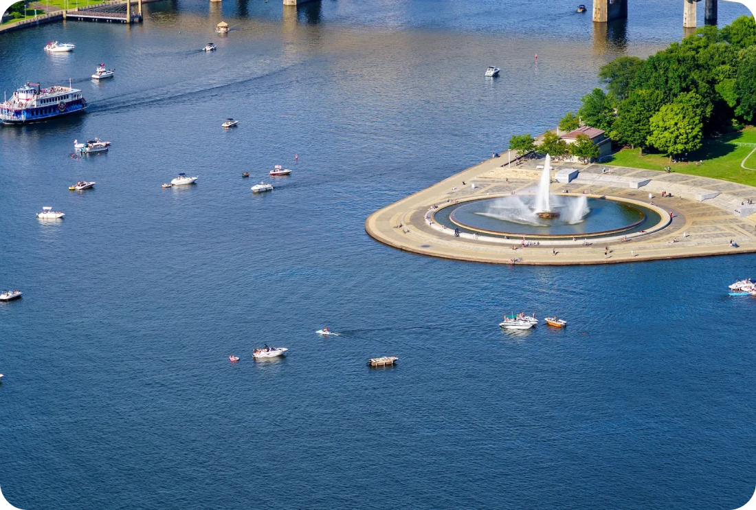 An aerial view of a lake with boats and a fountain in the middle.