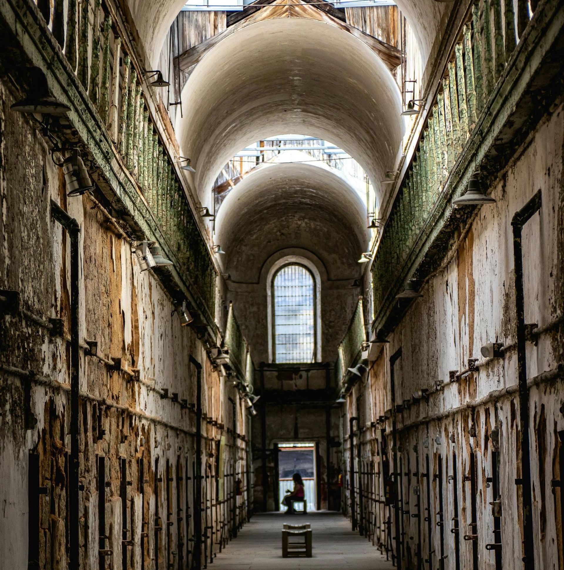 A long hallway in an old building with arches and a window.