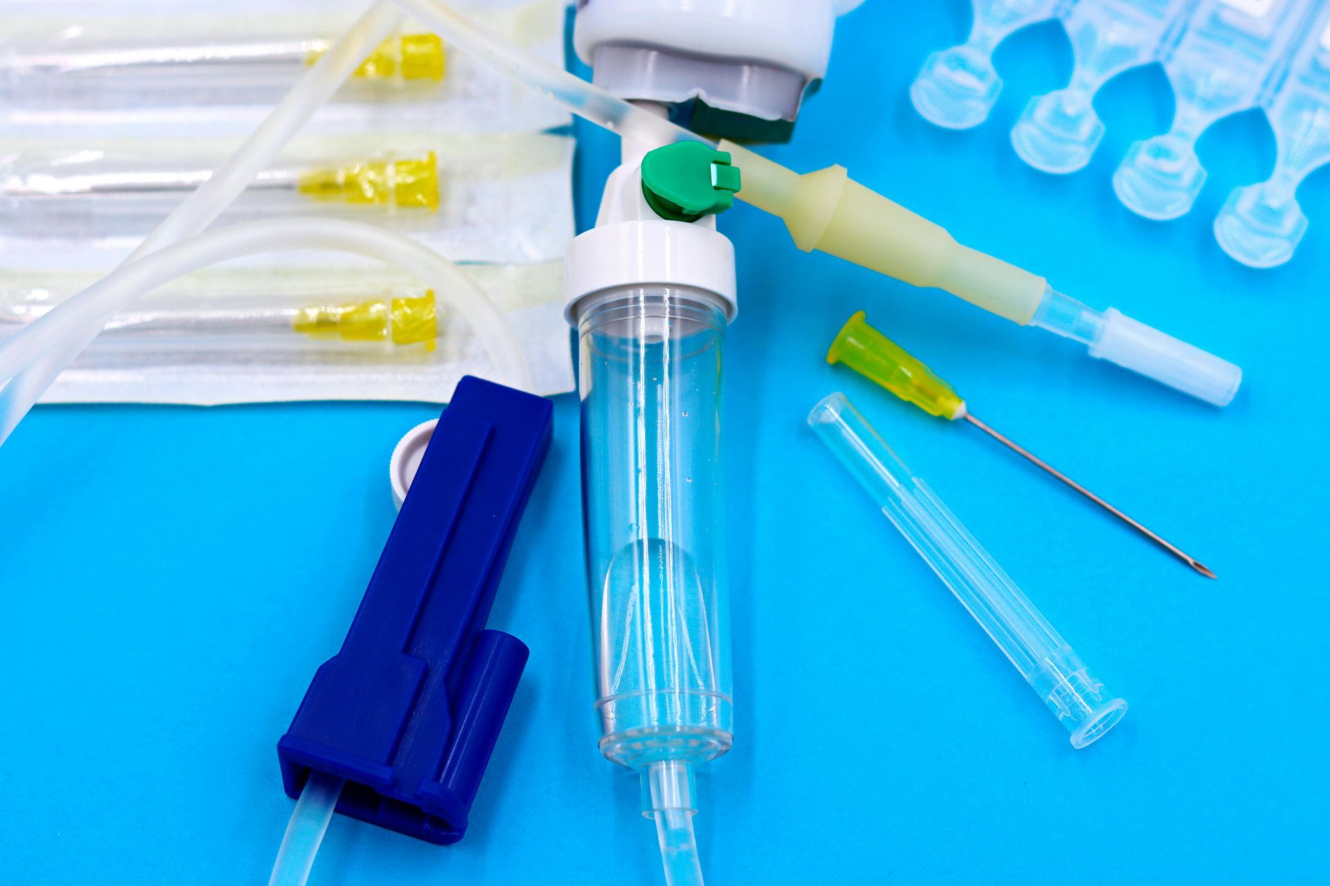 IV drip components on blue background: tubing, needles, and fluid bag connector.