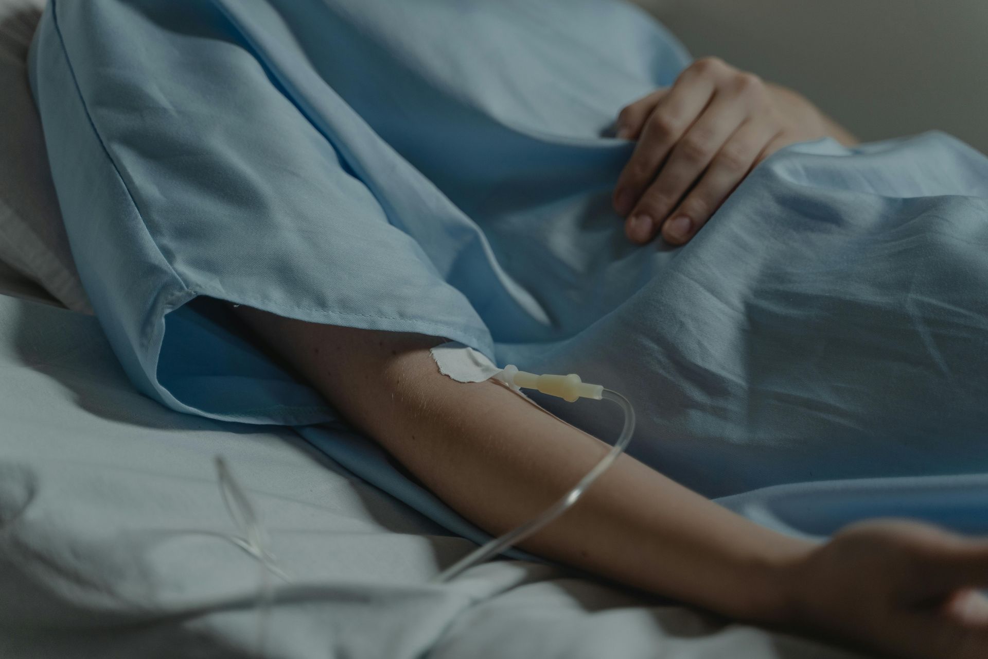 Person in a hospital bed with an IV drip in their arm.