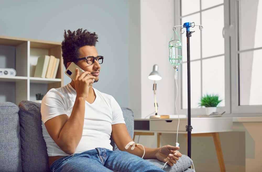 A man is sitting on a couch talking on a cell phone.