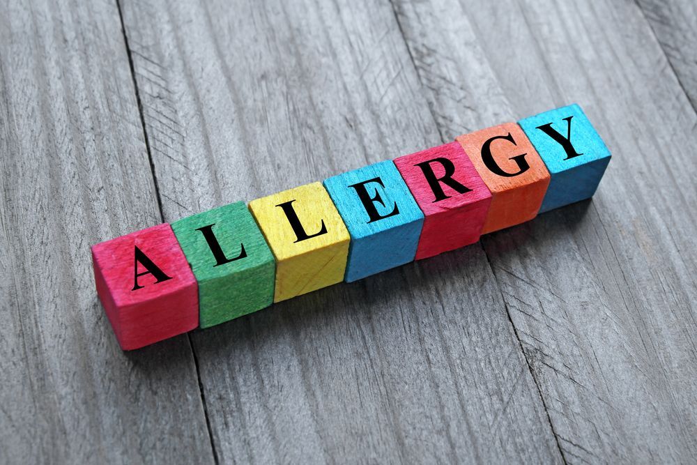 The word allergy is written on colorful wooden blocks on a wooden table.