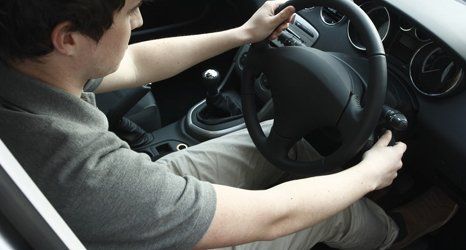 Young man turning the key in a modern car with black interior.