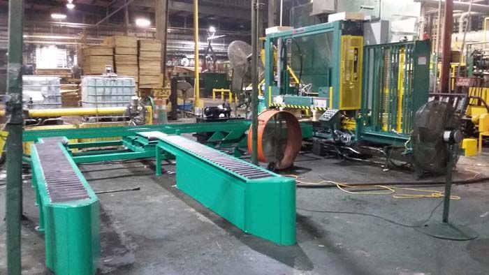 A green industrial conveyor system in a manufacturing warehouse setting.