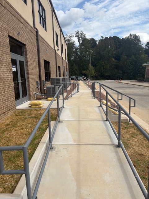 A close-up of a metal welding process, showing sparks and bright light where a rod connects to a dark metal fence frame.