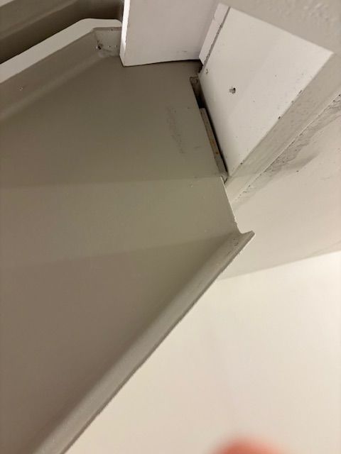 A close-up view of a beige interior corner bracket meeting a white door frame and painted wall.