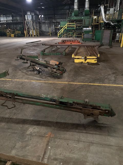 An industrial warehouse floor featuring various pieces of green and yellow heavy machinery equipment.