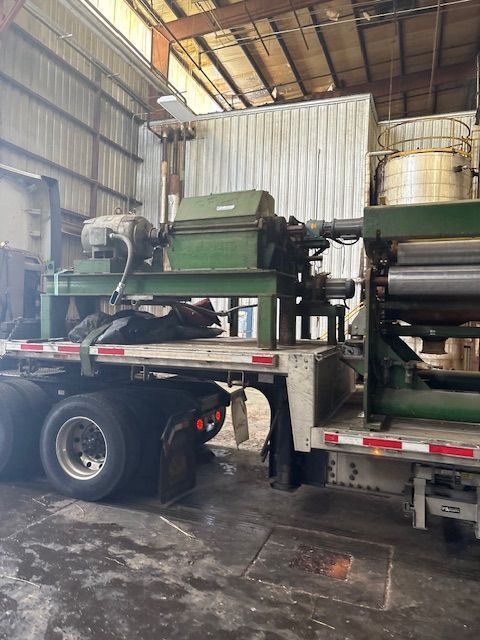 A large, green industrial machine mounted on the flatbed of a truck inside a warehouse.