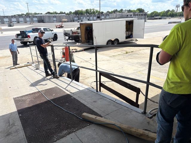 A close-up of a metal welding process, showing sparks and bright light where a rod connects to a dark metal fence frame.