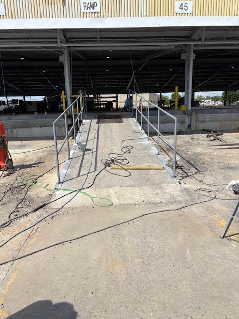 Concrete ramp with metal handrails leading into a covered loading dock area labeled 