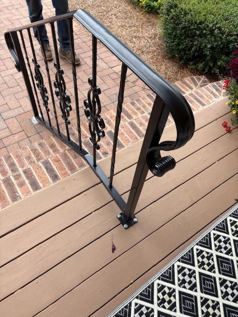 A close-up of a metal welding process, showing sparks and bright light where a rod connects to a dark metal fence frame.