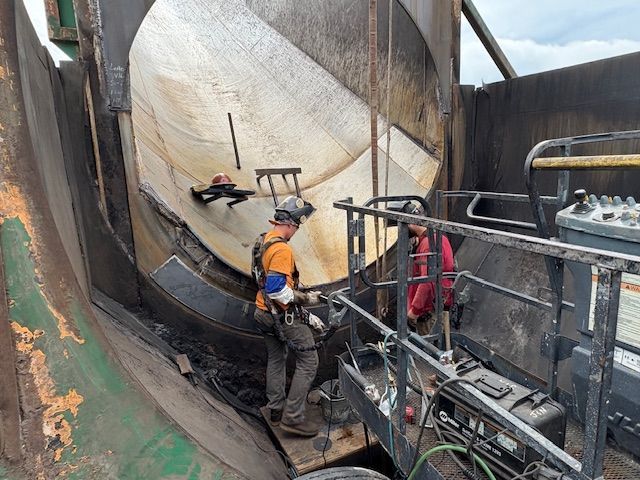 A close-up of a metal welding process, showing sparks and bright light where a rod connects to a dark metal fence frame.
