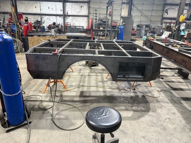 A close-up of a metal welding process, showing sparks and bright light where a rod connects to a dark metal fence frame.