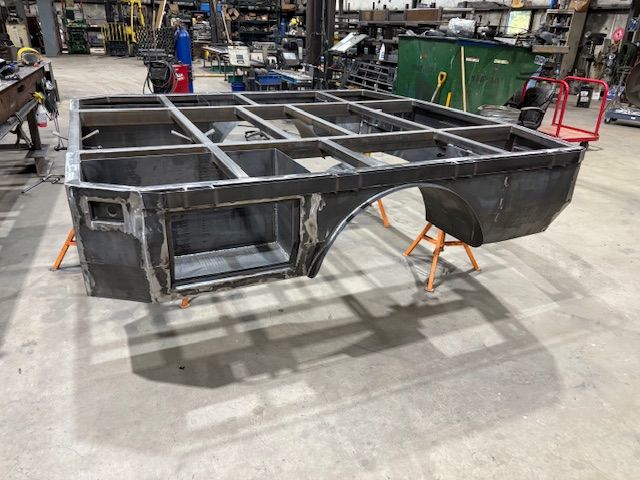 A close-up of a metal welding process, showing sparks and bright light where a rod connects to a dark metal fence frame.