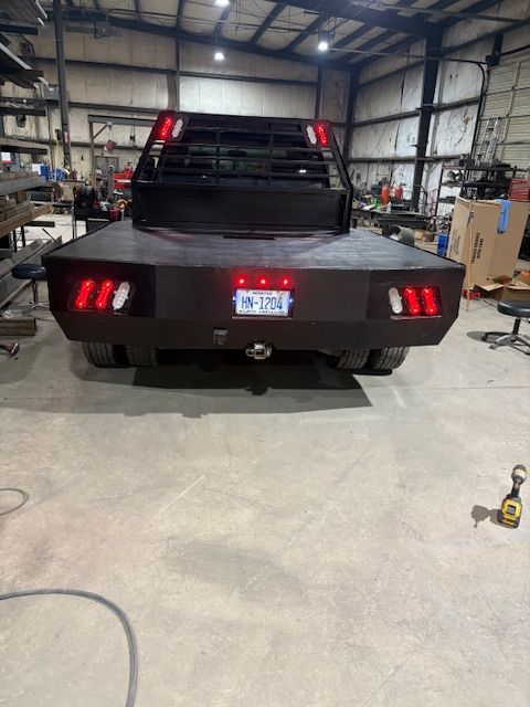 A close-up of a metal welding process, showing sparks and bright light where a rod connects to a dark metal fence frame.