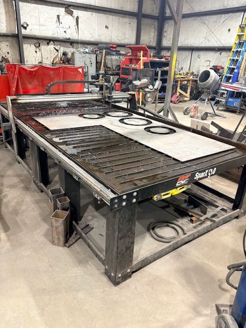 A close-up of a metal welding process, showing sparks and bright light where a rod connects to a dark metal fence frame.