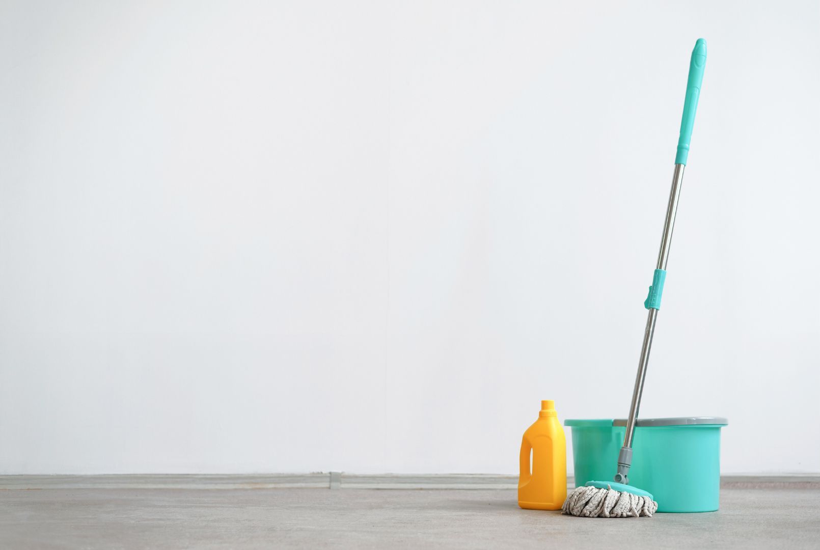 A mop , bucket , and bottle of cleaning supplies on a wooden floor.