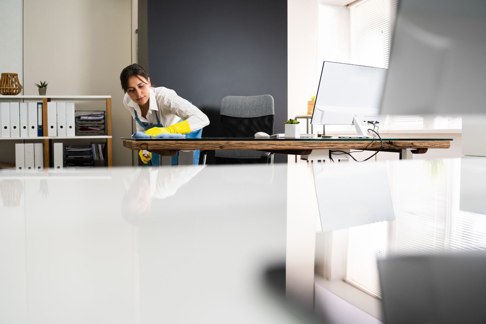 A woman is cleaning a desk in an office.
