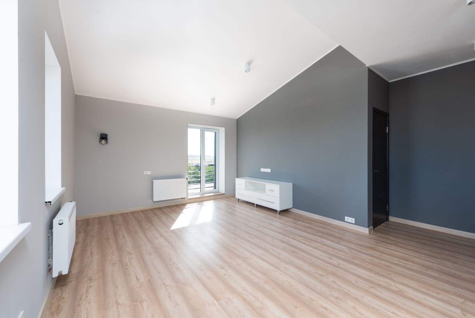 An empty living room with wooden floors and gray walls.