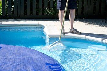 Man cleaning pool with net - Pool cleaning in Whittier, CA