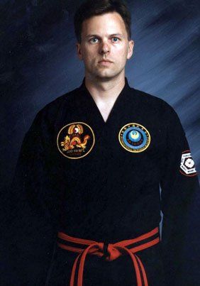 A man in a black karate uniform with a red belt