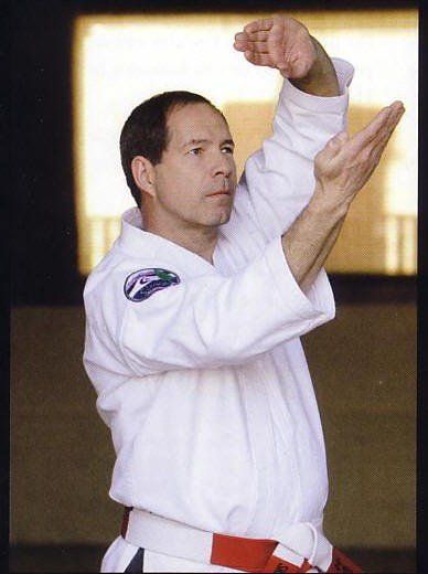 A man in a white karate uniform with a red belt