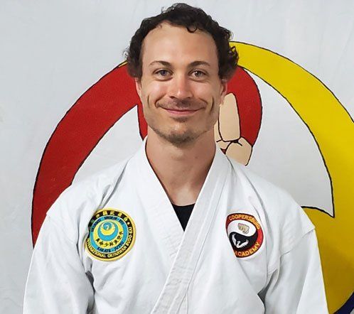 A man in a white karate uniform is smiling for the camera