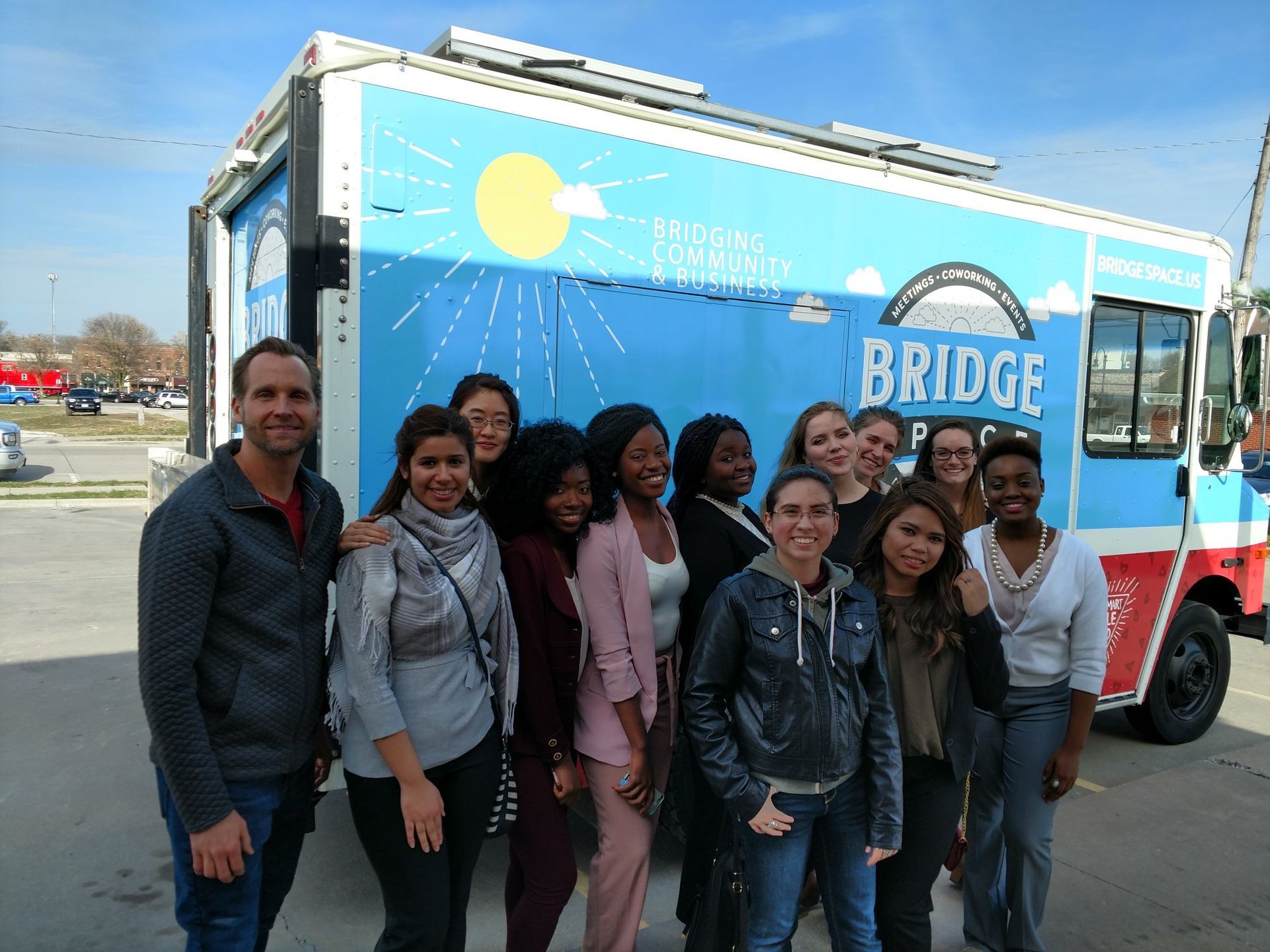 A group of people standing in front of a bridge food truck