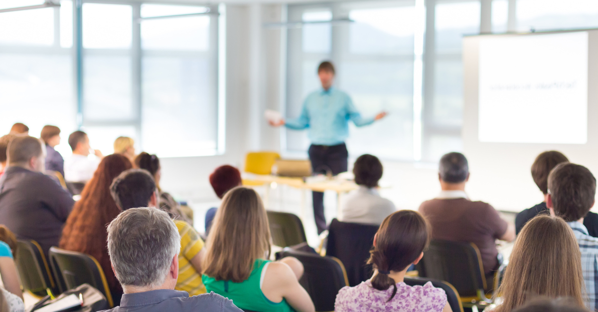 Audience attending a business presentation in a bright coworking event space, with a speaker present