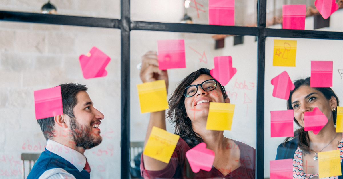 Coworking team collaborating during a strategy session with sticky notes on a glass wall at Bridge Space in downtown Lee’s Summit, ideal for brainstorming and workshops