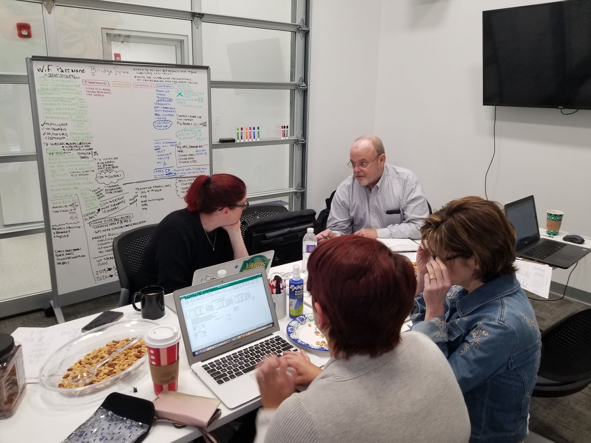 A group of people are sitting around a table with laptops.