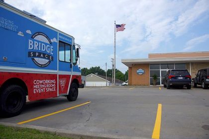 A bridge space truck is parked in a parking lot in front of a building.