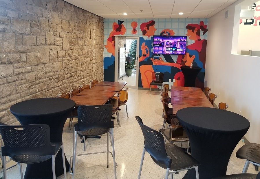A room with tables and chairs and a mural on the wall.