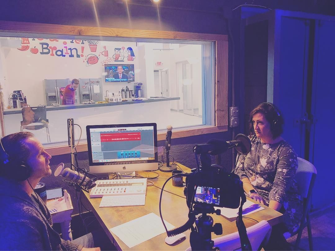 Two women are sitting in front of a microphone in a studio.