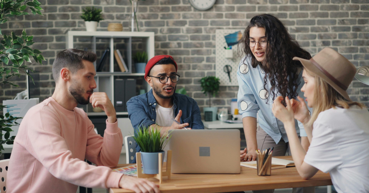 Group of young professionals collaborating around a laptop inside a bright coworking environment sim