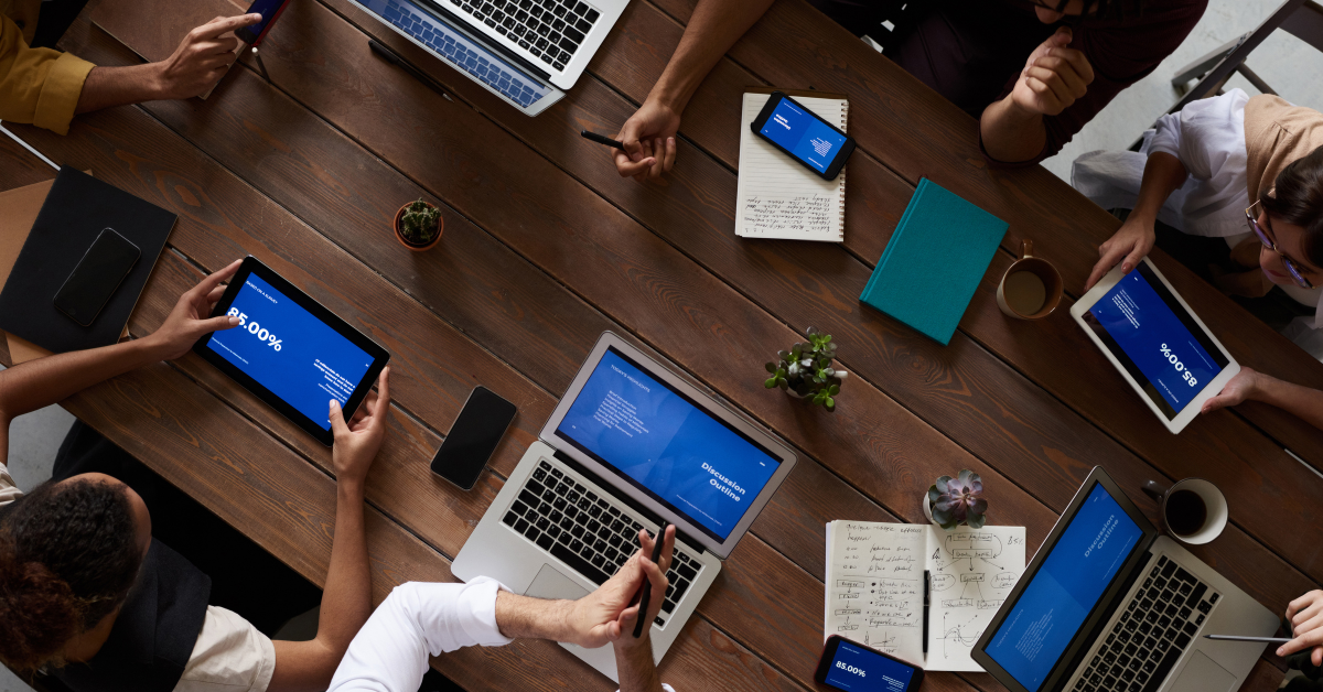 People working together around a shared table with laptops and tablets inside a collaborative works