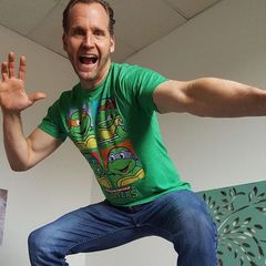 A man wearing a green shirt with teenage mutant ninja turtles on it