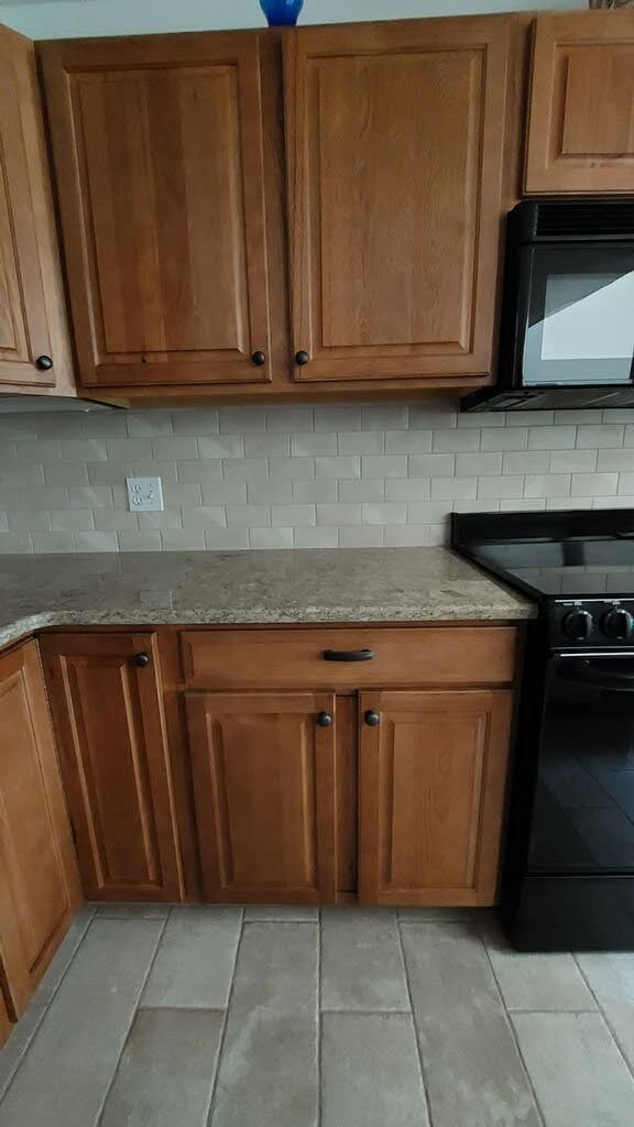a kitchen with wooden cabinets , granite counter tops , a stove and a microwave .