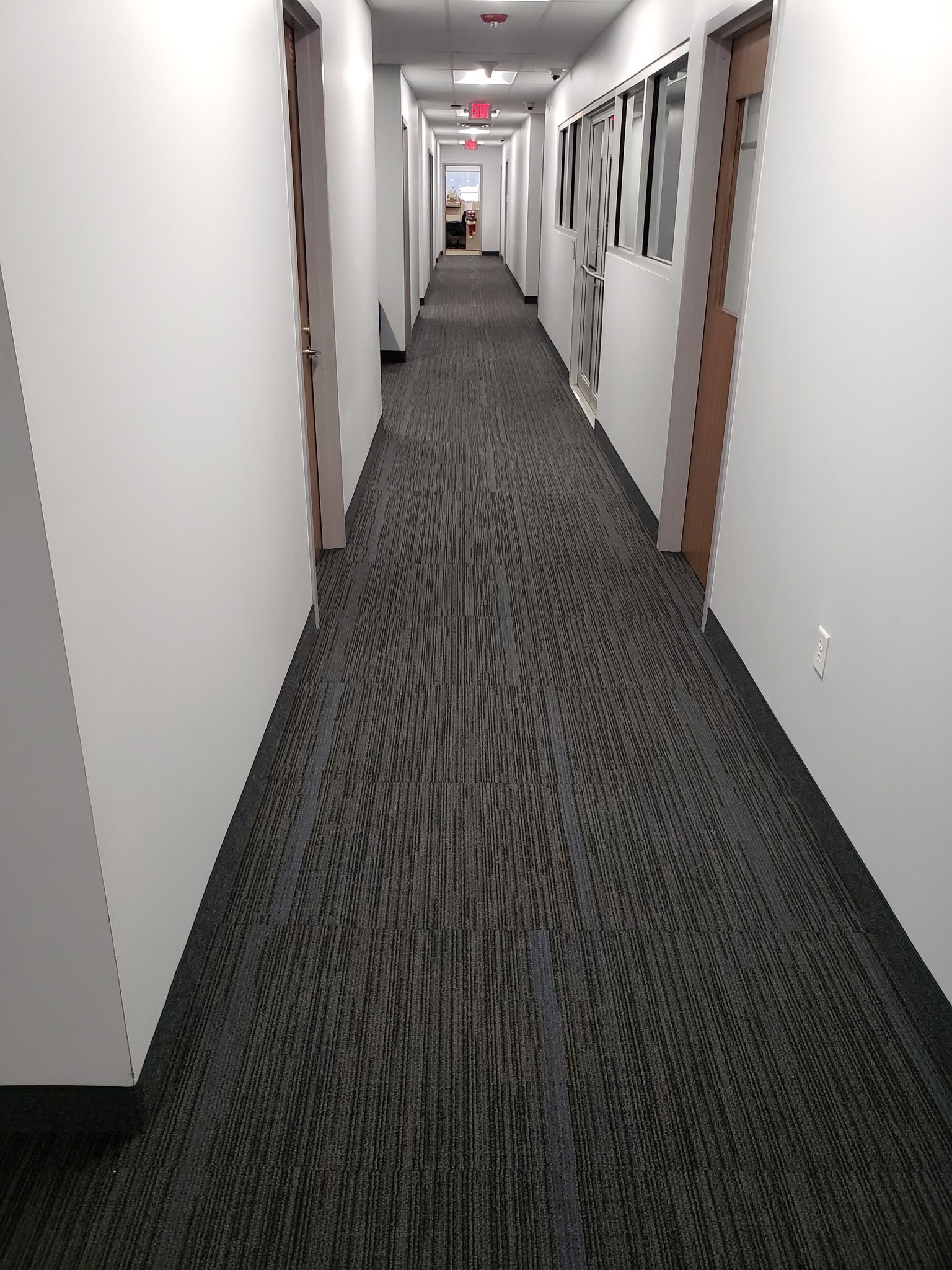 a long hallway with a red exit sign above it