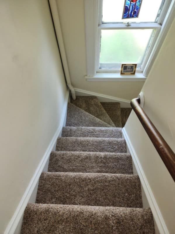 a set of stairs leading up to a window with a stained glass window .
