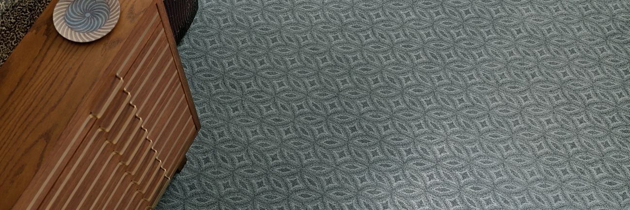 a blue carpet with a geometric pattern is next to a wooden dresser .