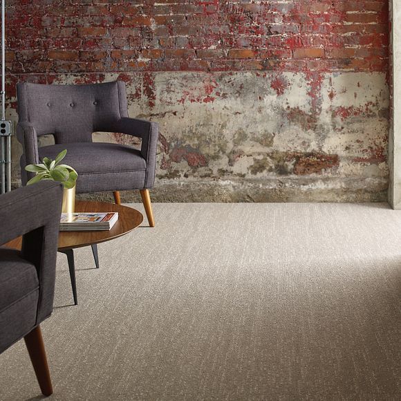 a living room with two chairs , a table , and a brick wall .
